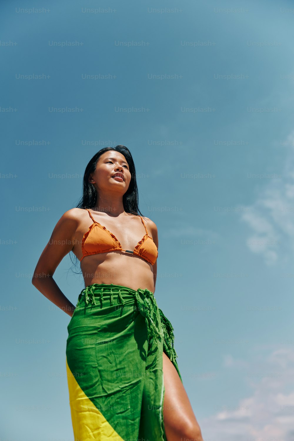 a woman in a bikini top and green and yellow skirt