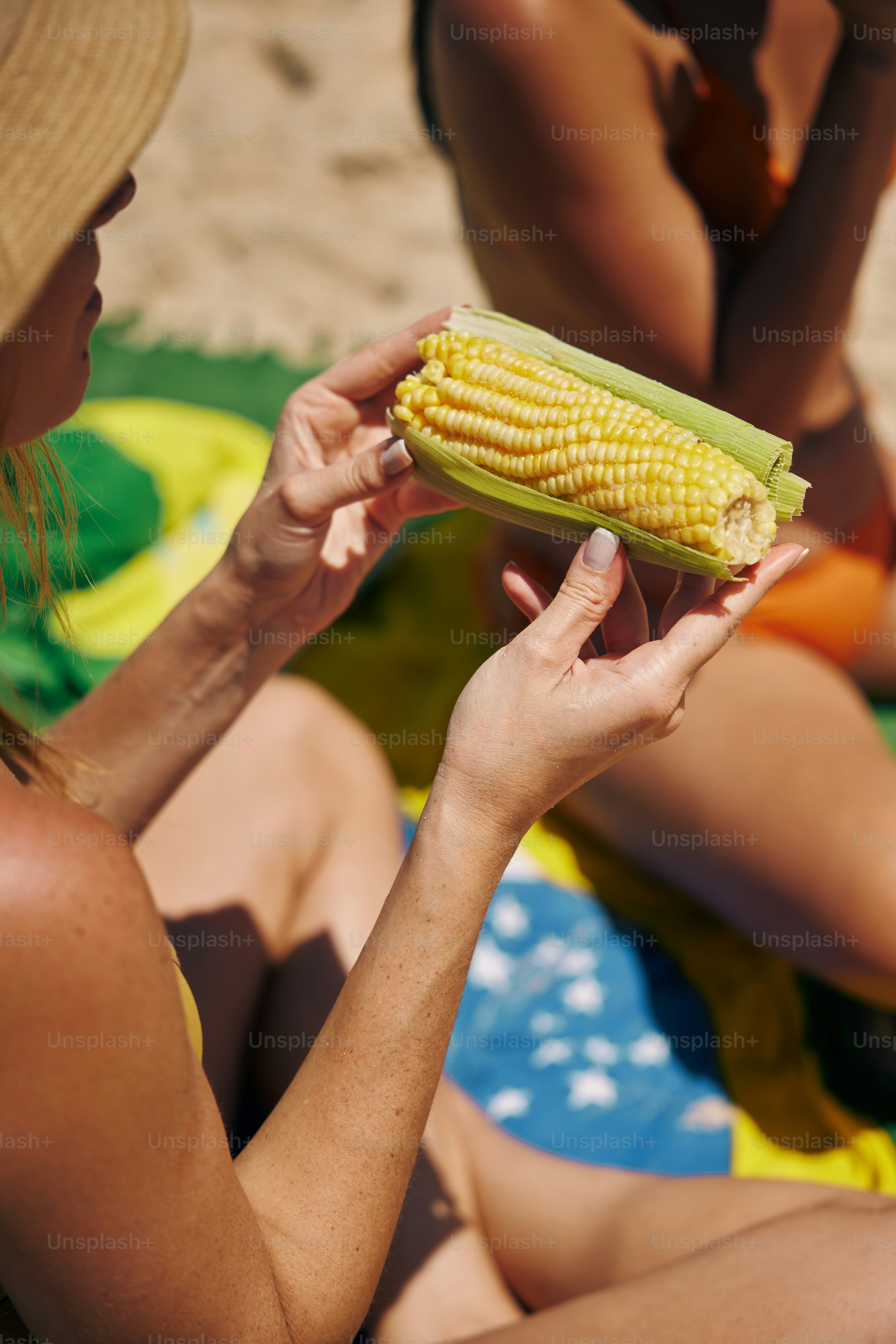 a woman is holding a corn on the cob