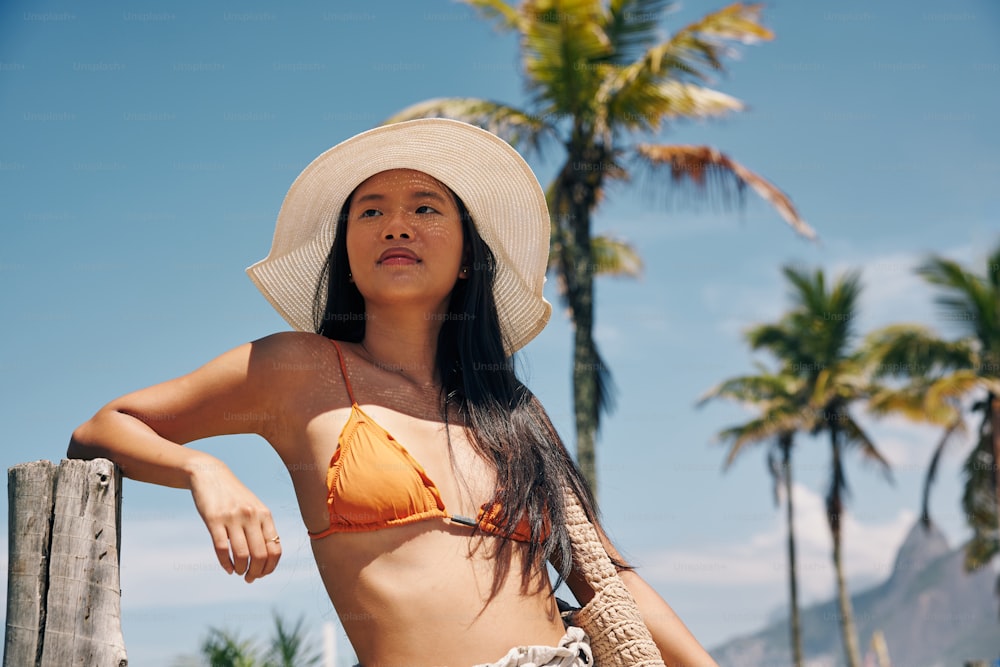 a woman in a bikini and a hat on a beach