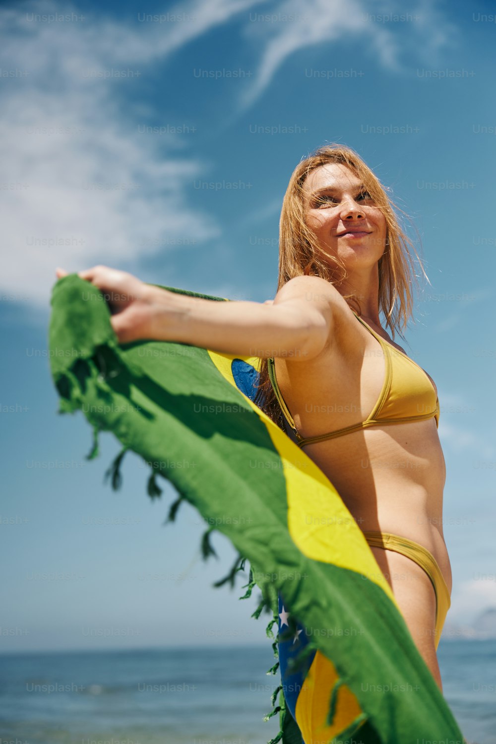 Eine Frau im Bikini, die ein grün-gelbes Handtuch hält