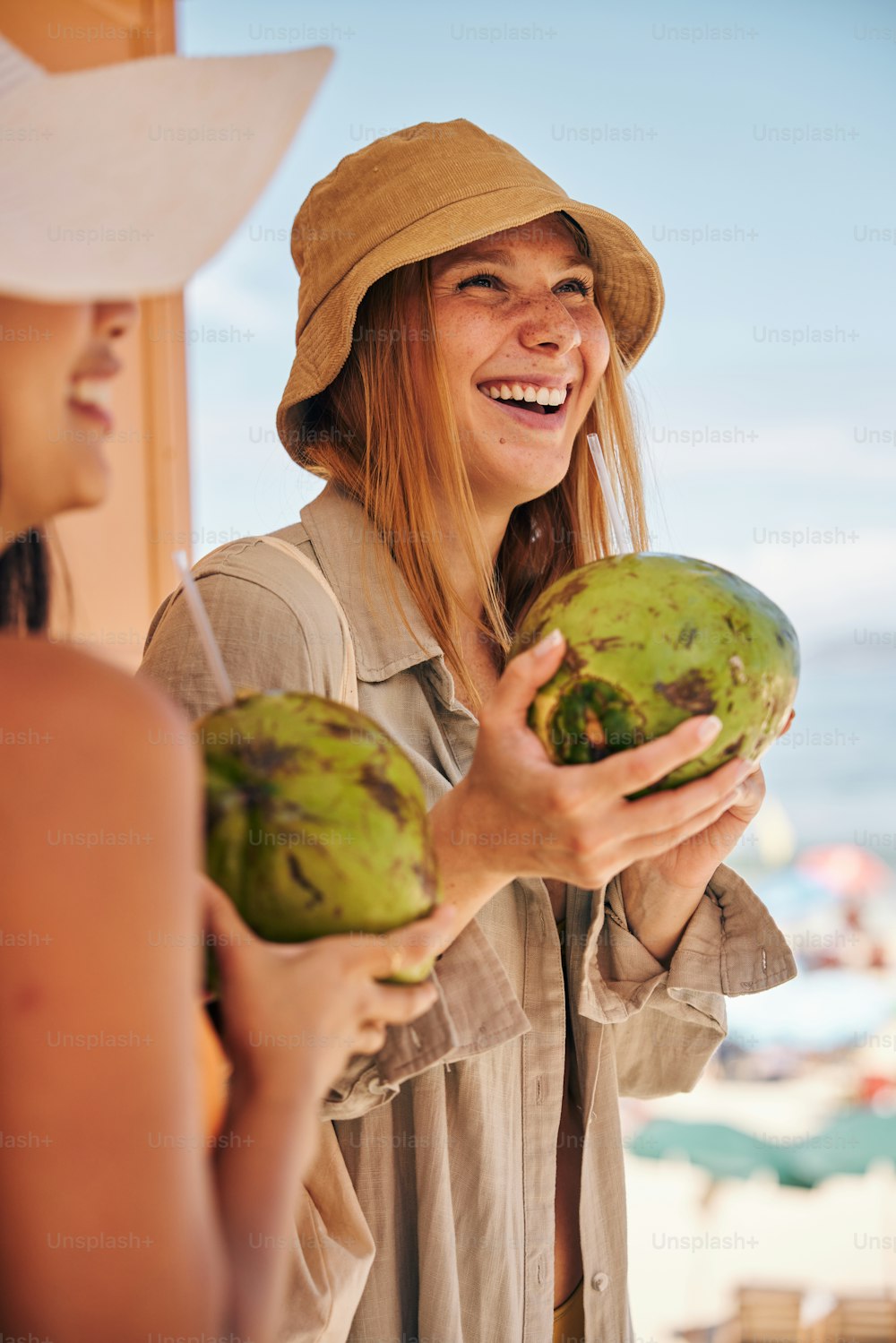 a woman wearing a hat holding a coconut