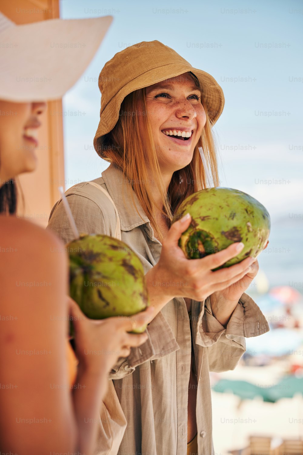 eine Frau mit Hut, die eine Kokosnuss hält