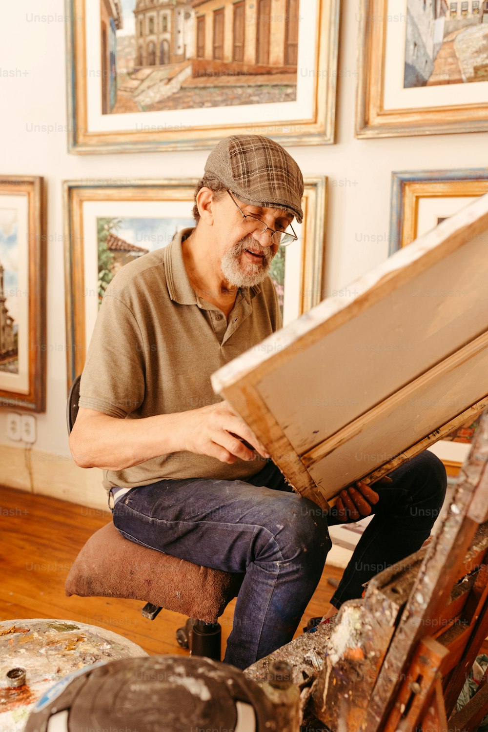 um homem sentado em um banquinho trabalhando em uma obra de arte