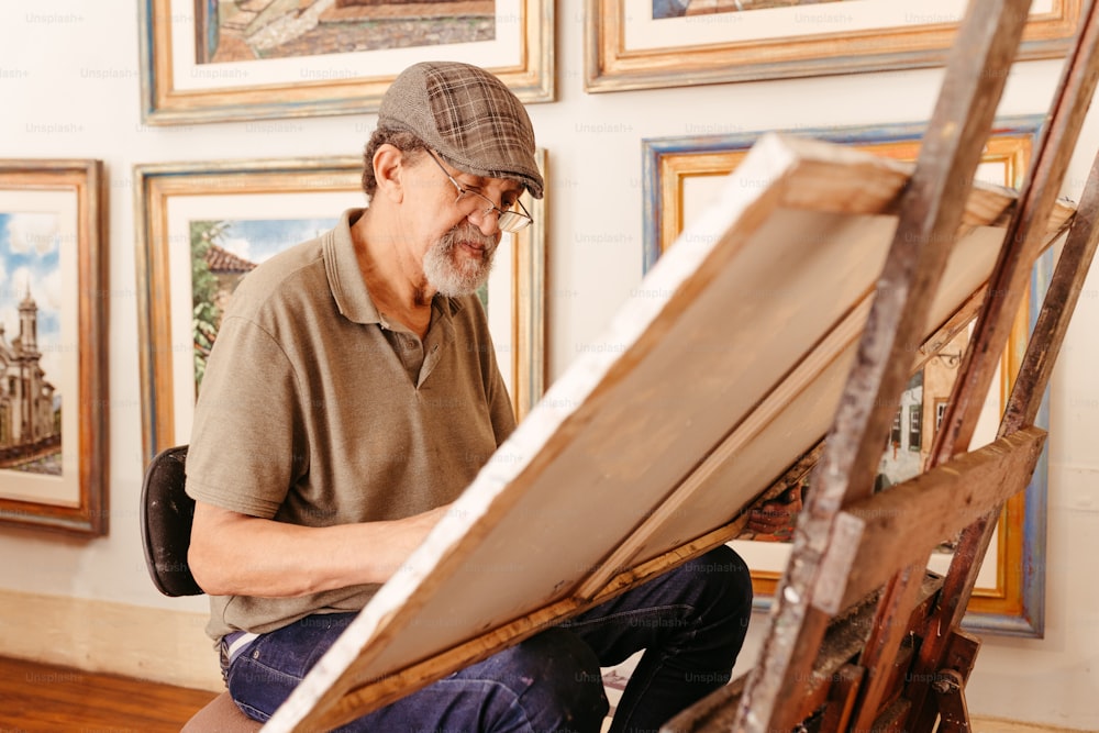 Un uomo seduto di fronte a un dipinto su un cavalletto