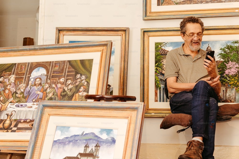 Ein Mann sitzt auf dem Boden vor einem Haufen Gemälde