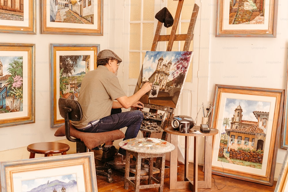 a man sitting in a chair in front of paintings