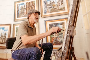 a man sitting in front of a painting on a easel