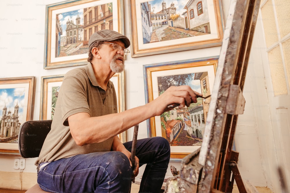 Ein Mann sitzt vor einem Gemälde auf einer Staffelei