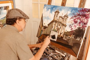 um homem sentado em frente a uma pintura de uma igreja