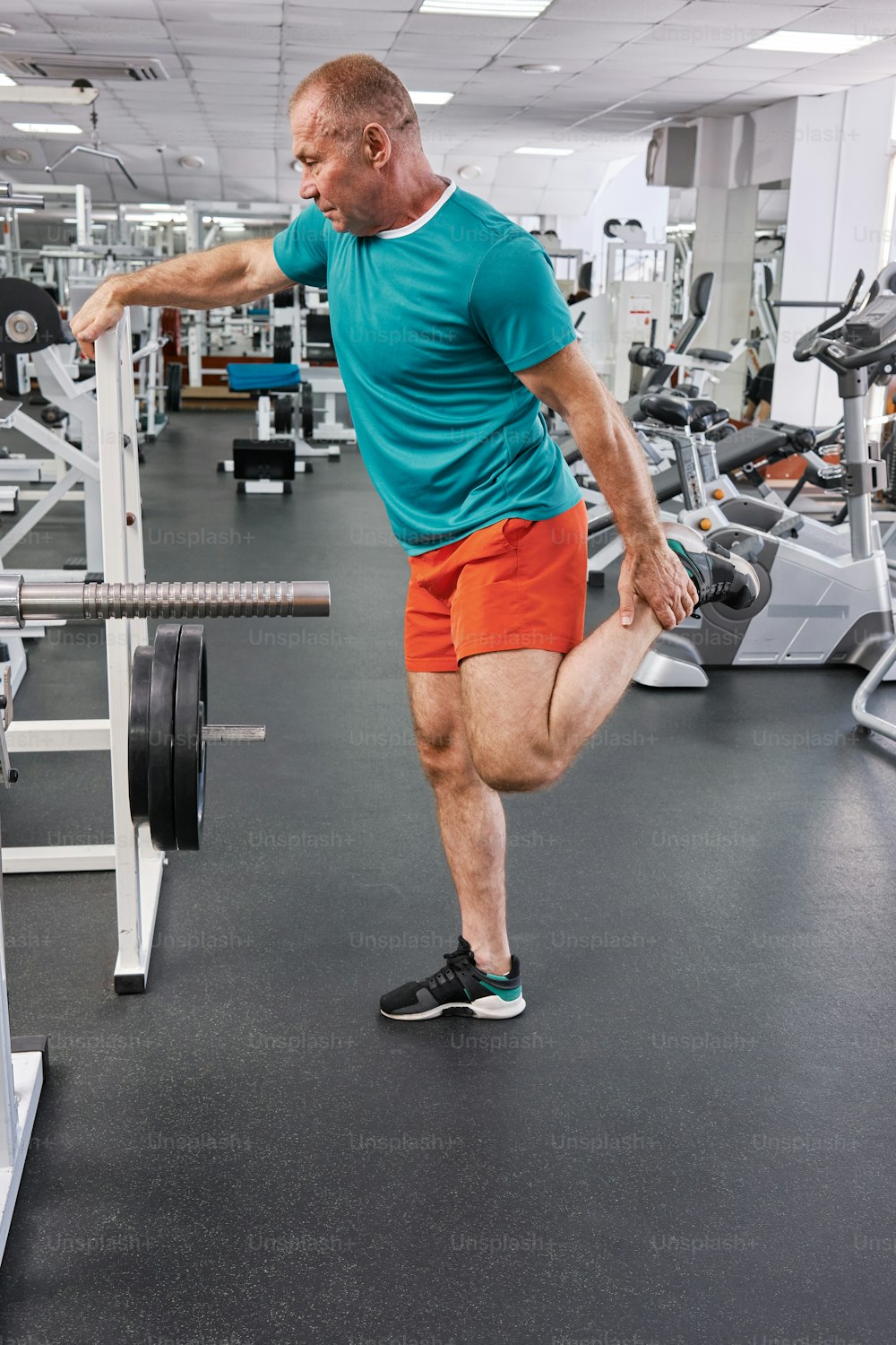 Un hombre en un gimnasio haciendo ejercicios con una barra