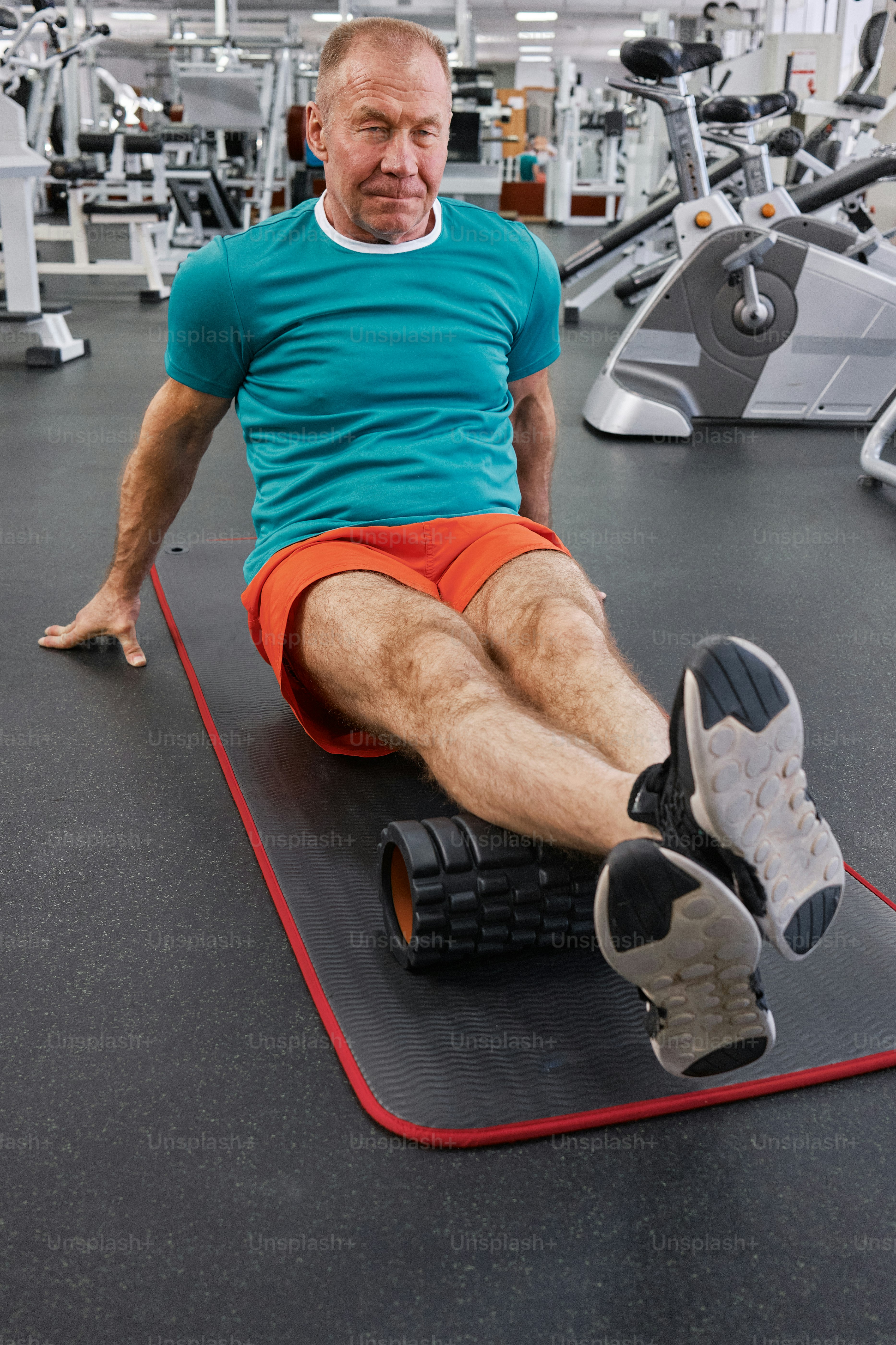 a man sitting on a mat in a gym