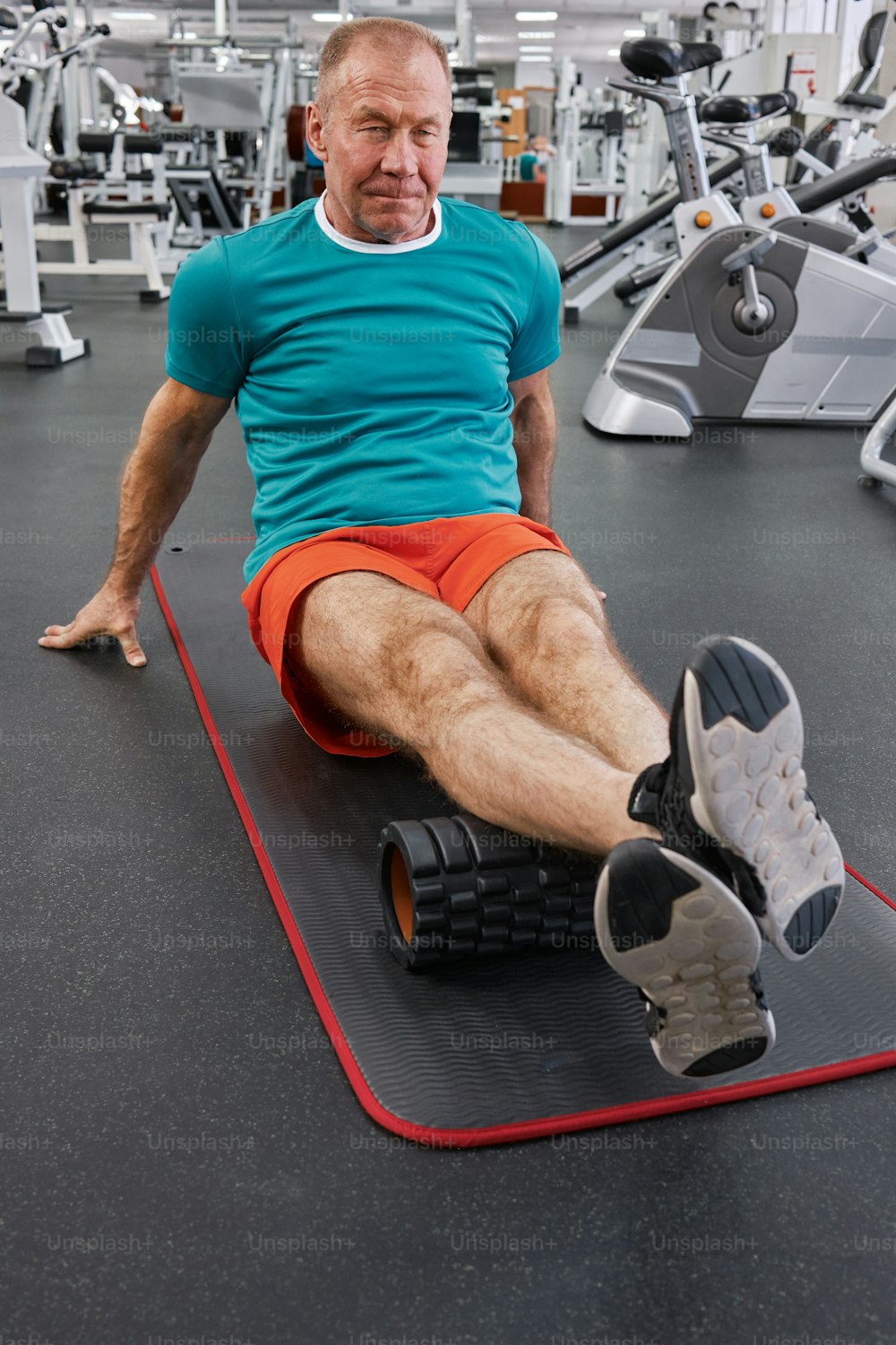 um homem sentado em um tapete em um ginásio