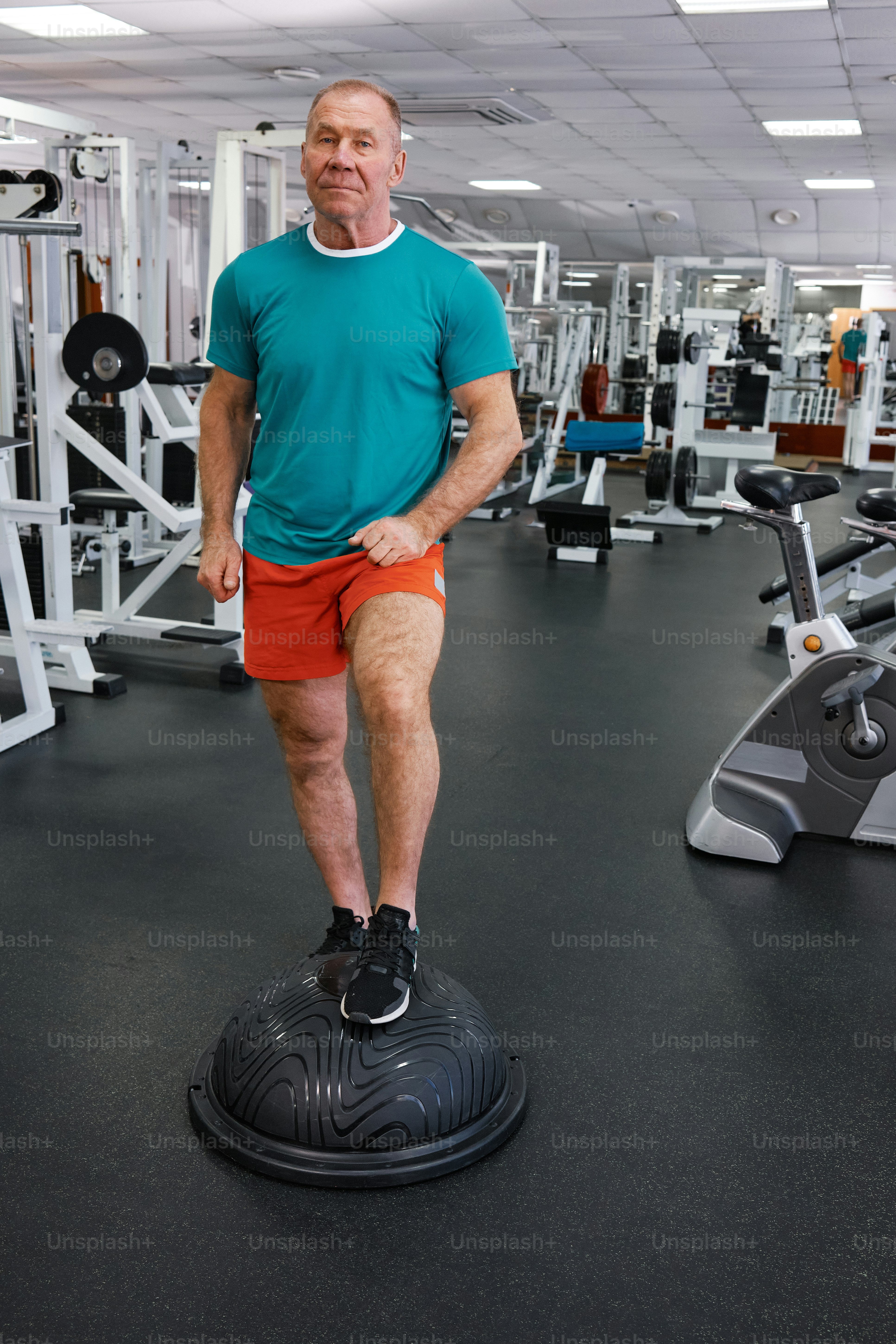 a man standing on top of a black object in a gym