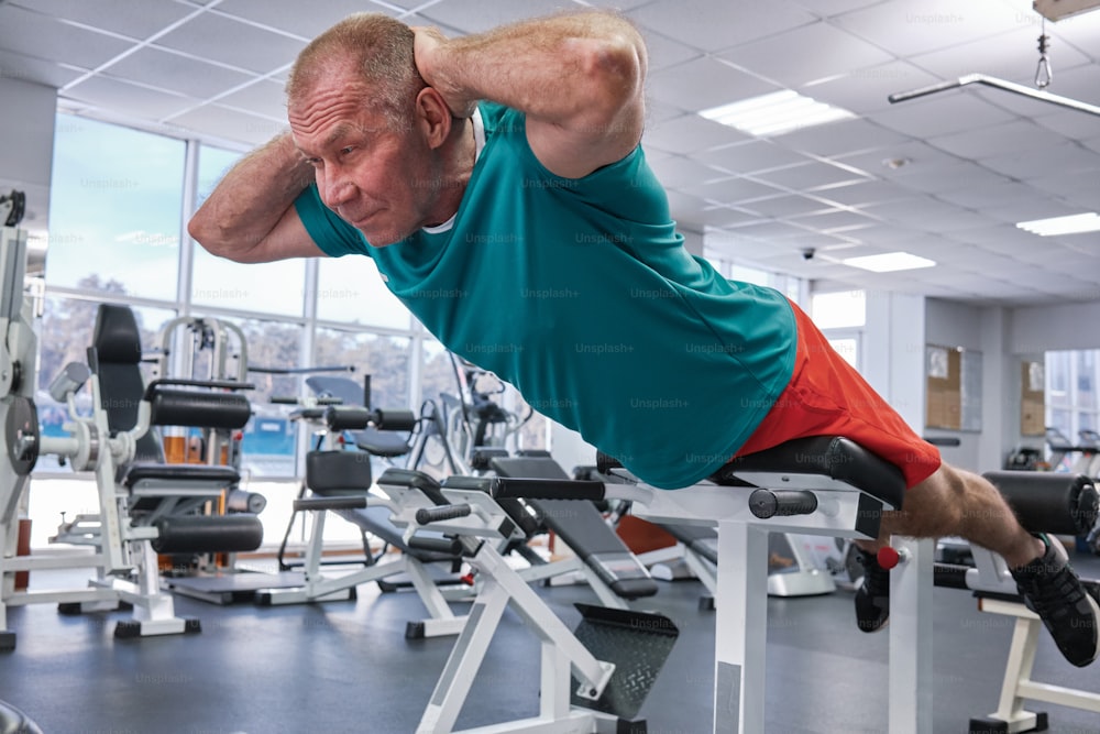 Un hombre haciendo flexiones en una máquina en un gimnasio