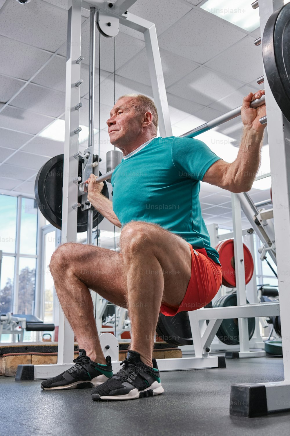 a man squats on a bench in a gym