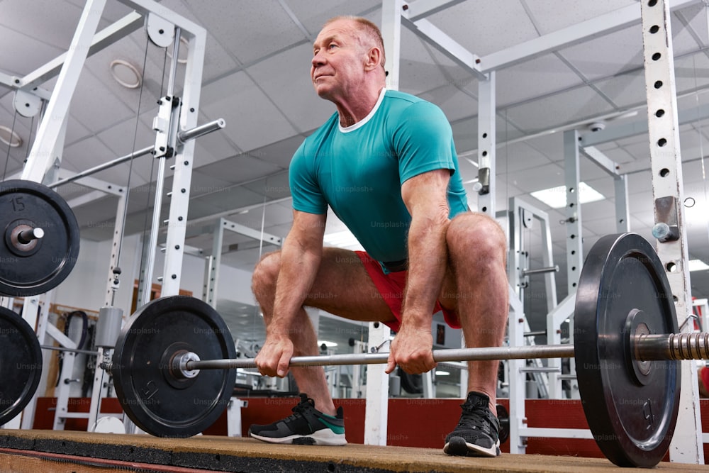a man squatting on a barbell in a gym