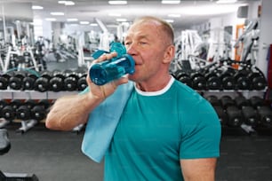 a man in a gym drinking from a water bottle