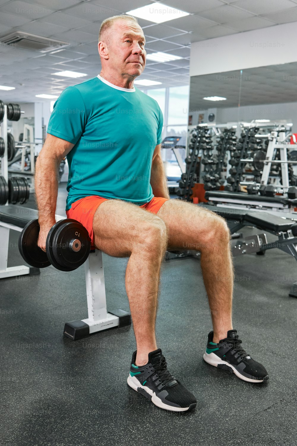a man sitting on a bench with a dumbbell