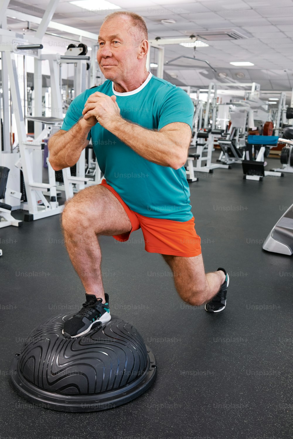 a man is squatting on a tire in a gym