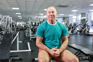 Un homme assis sur un banc dans un gymnase