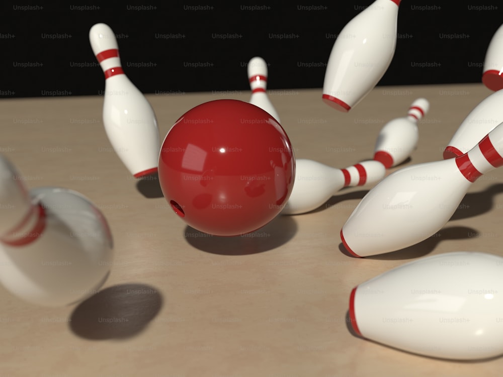a group of white and red bowling pins and a red ball
