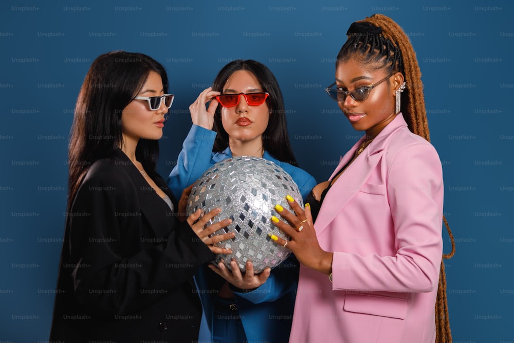 um grupo de mulheres de pé uma ao lado da outra segurando uma bola de discoteca