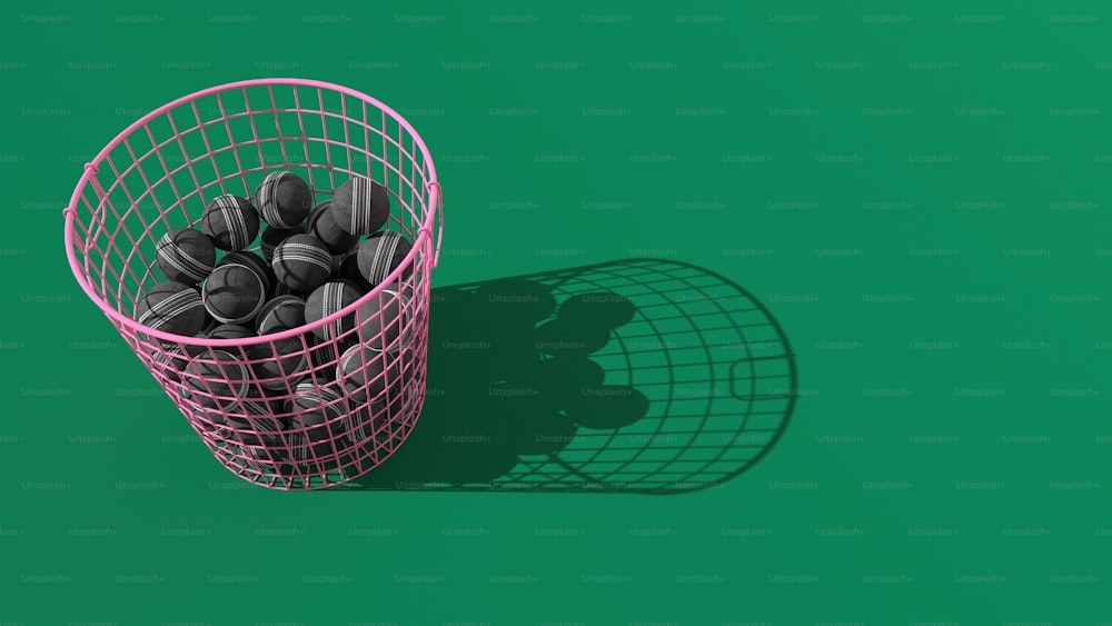 a pink wire basket filled with balls on a green background