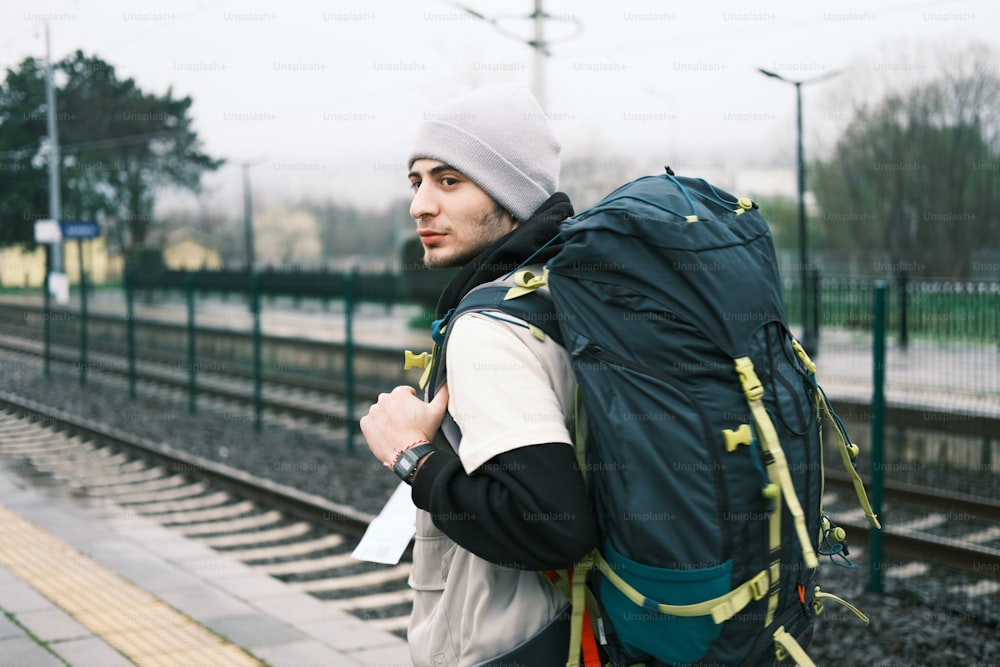 Un hombre con una mochila esperando un tren