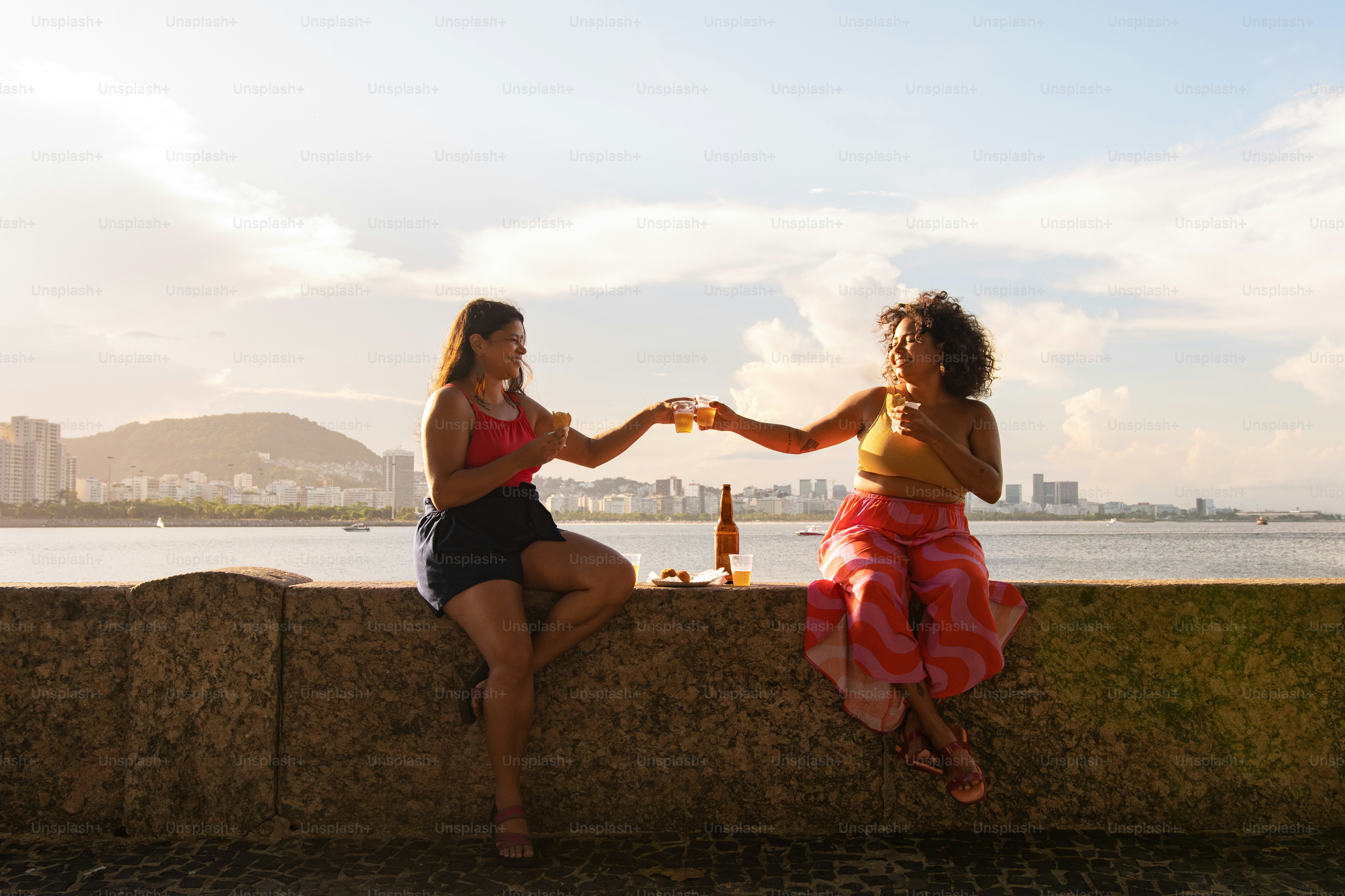 a couple of women sitting on top of a stone wall