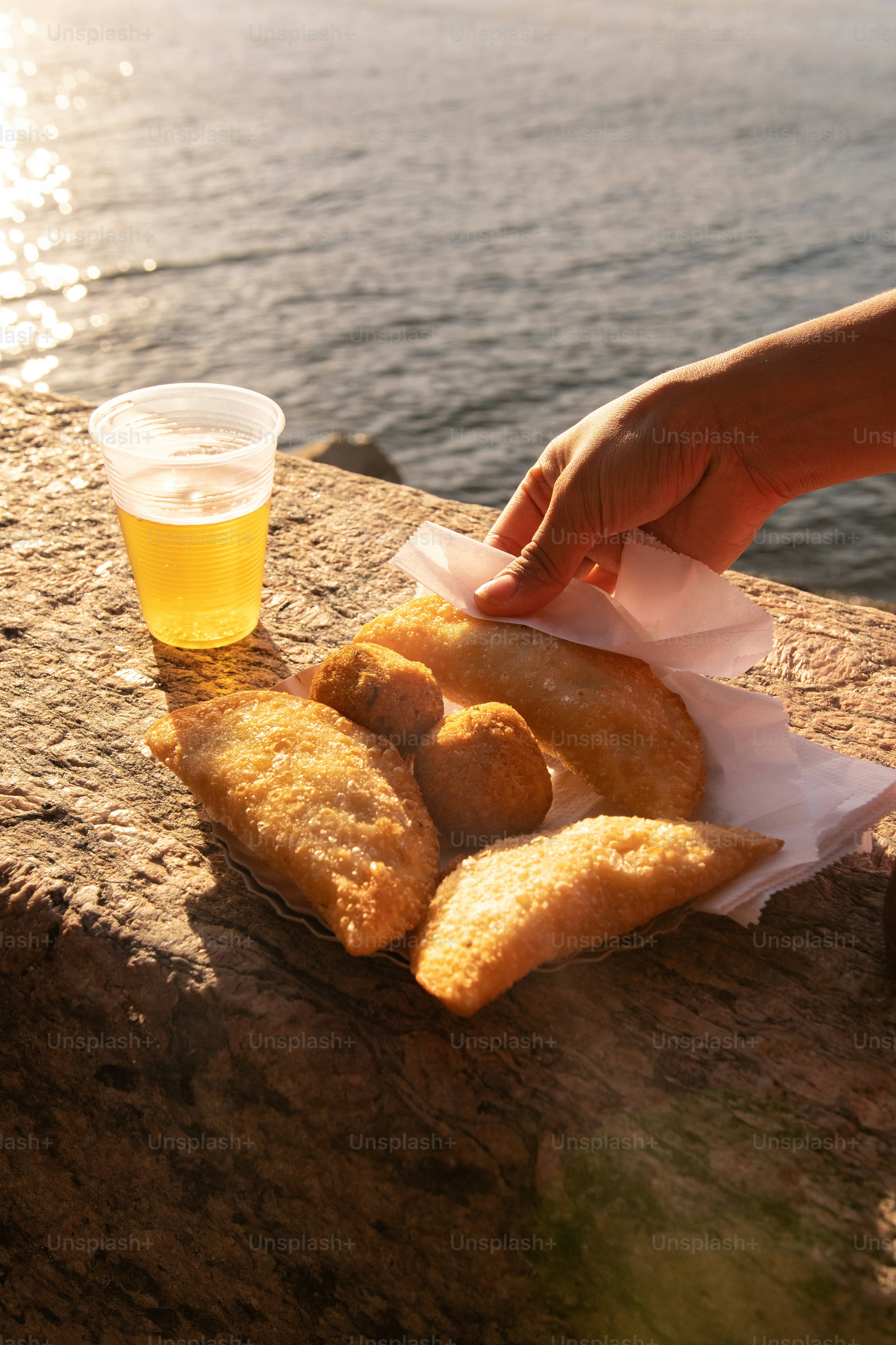 a person reaching for some food next to a glass of beer