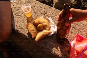 a person holding a beer and some food