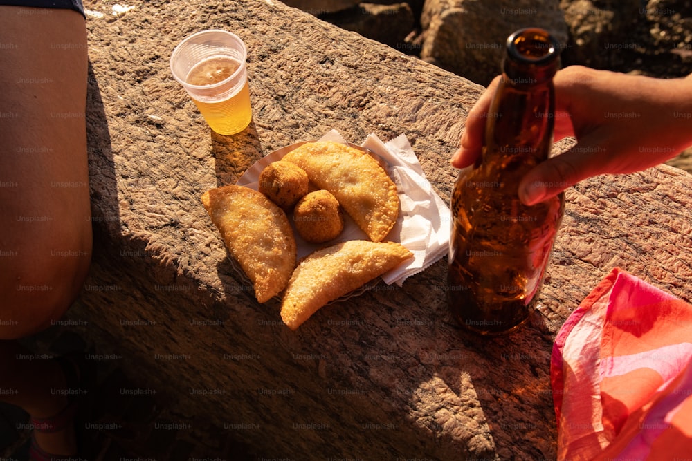 a person holding a beer and some food