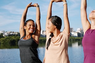 a group of women standing next to each other in front of a body of water