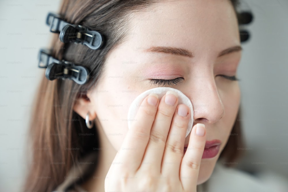 a woman with her eyes closed holding a napkin to her nose