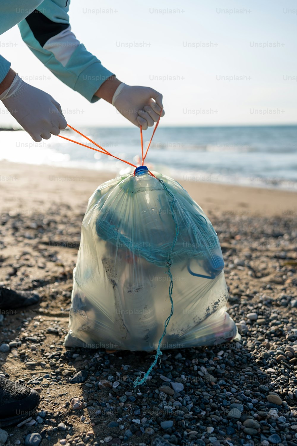 eine Person, die eine Plastiktüte am Strand hält