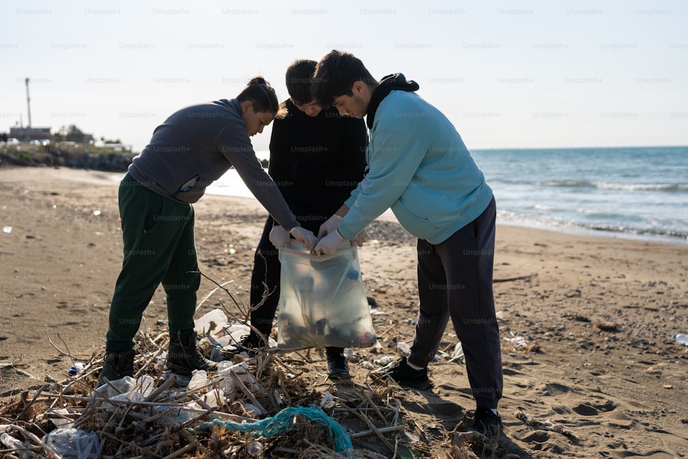 Tres personas recogiendo basura en una playa