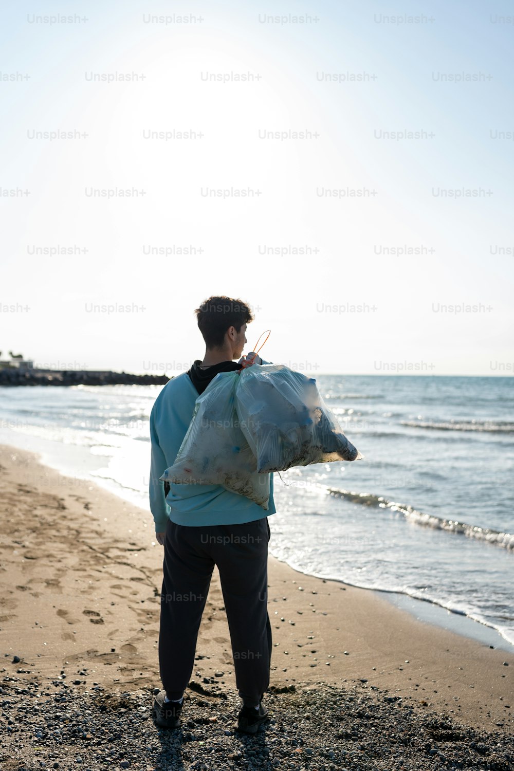 um homem em pé em uma praia segurando um saco