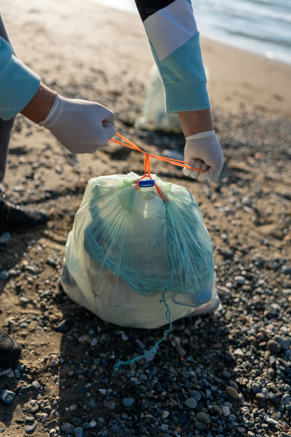 a person holding a bag of garbage on a beach