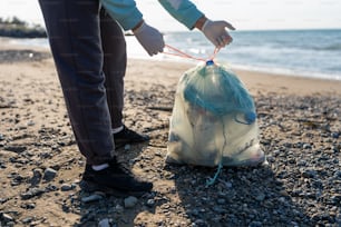 a person standing on a beach with a bag of garbage