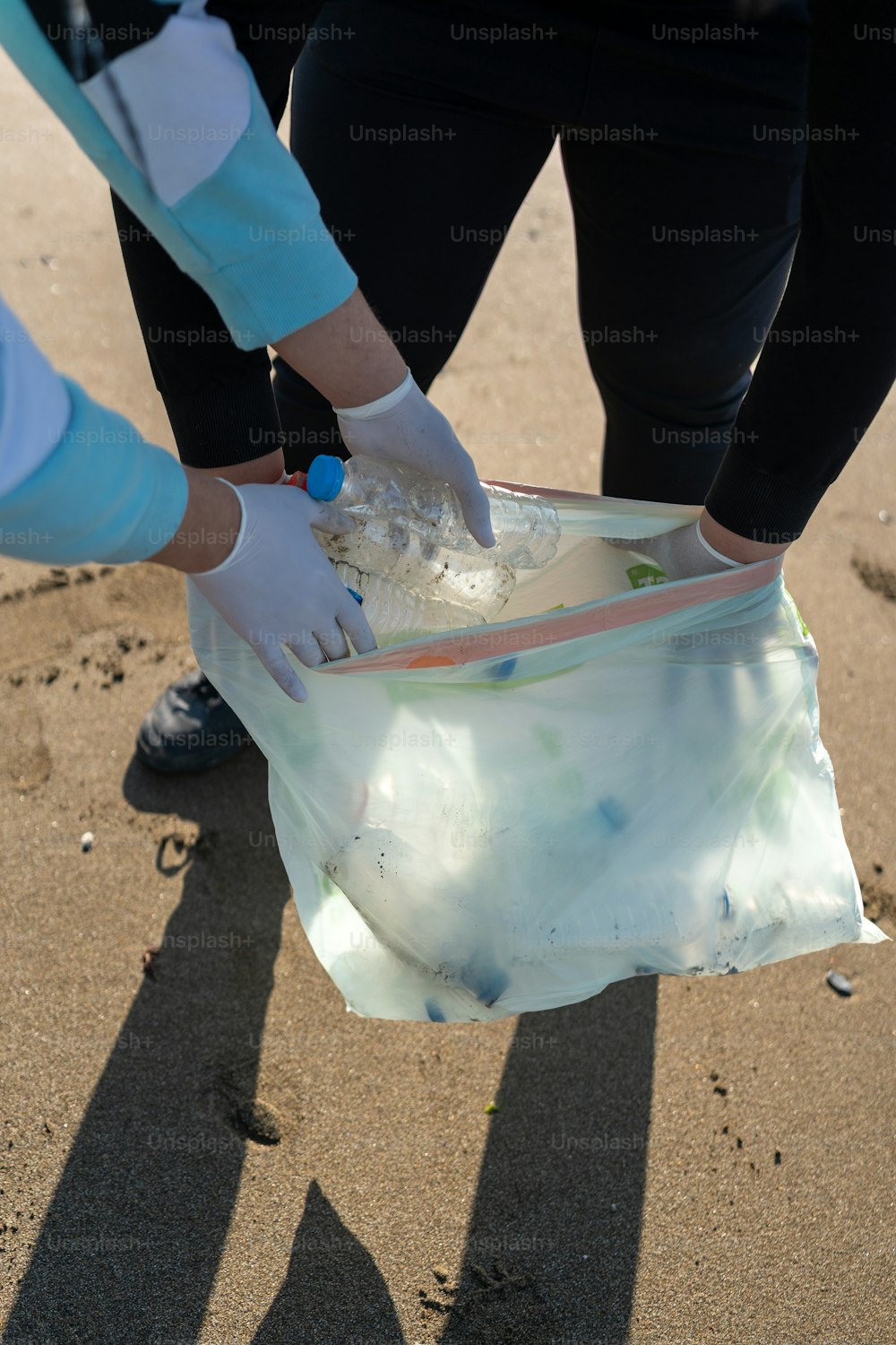 eine Person, die eine Plastiktüte an einem Strand hält