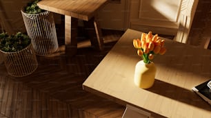 a yellow vase with orange flowers on a wooden table