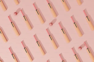 un muro rosa con un mazzo di bastoncini di legno e un gomitolo di filo