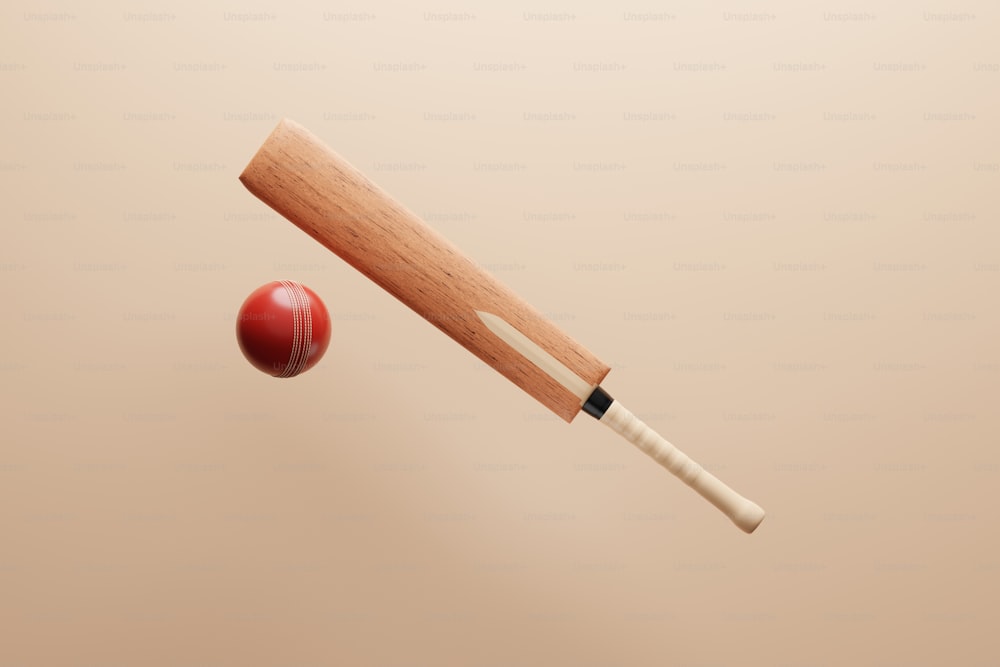 a wooden cricket bat hitting a red ball