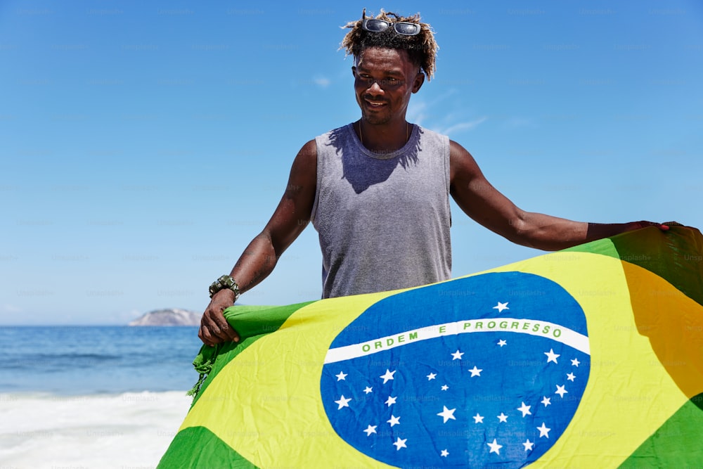 a man holding a large flag on the beach