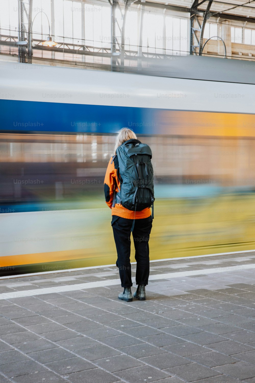 Una persona parada en una plataforma con un tren en el fondo