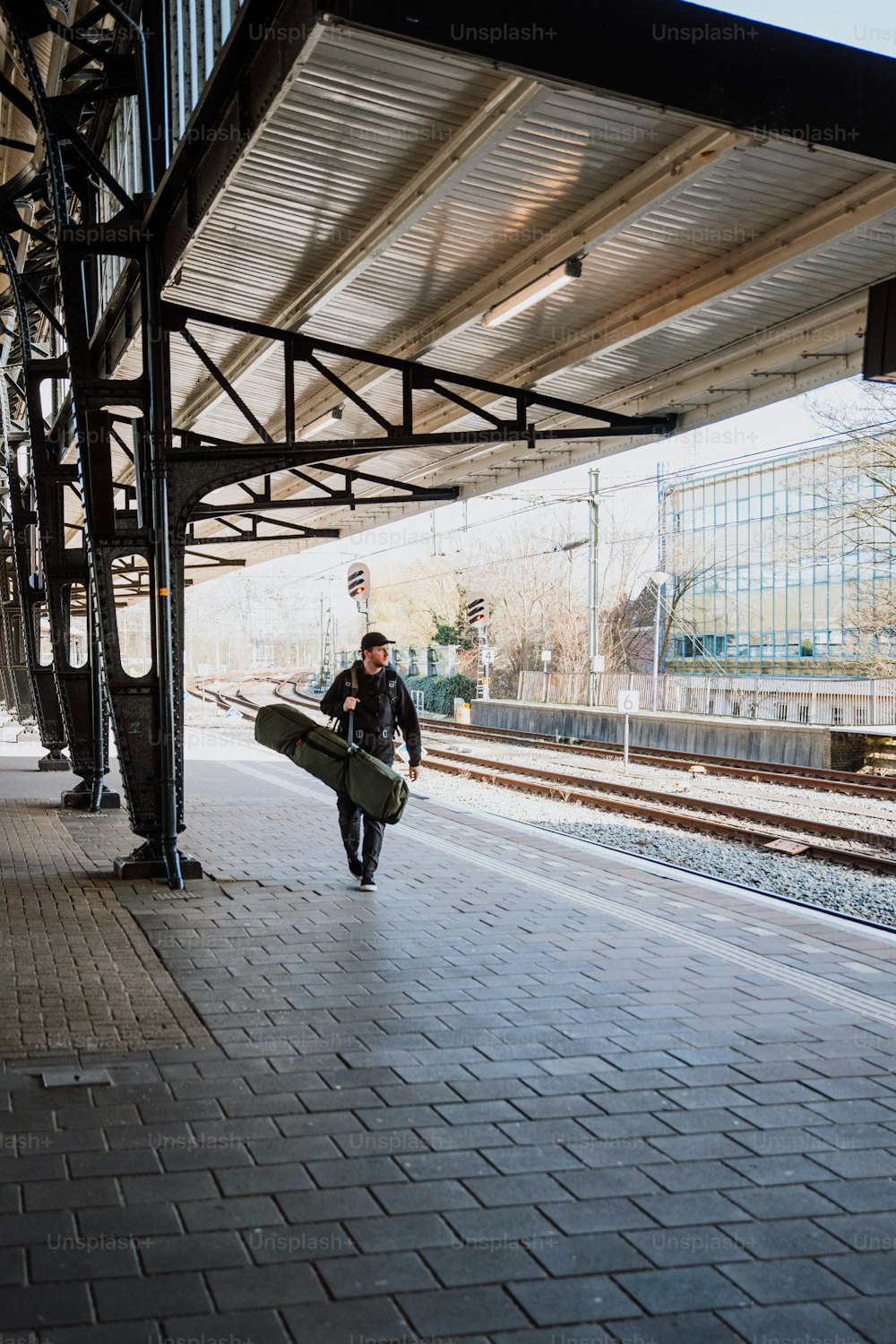 a man with a surfboard walking down a train platform