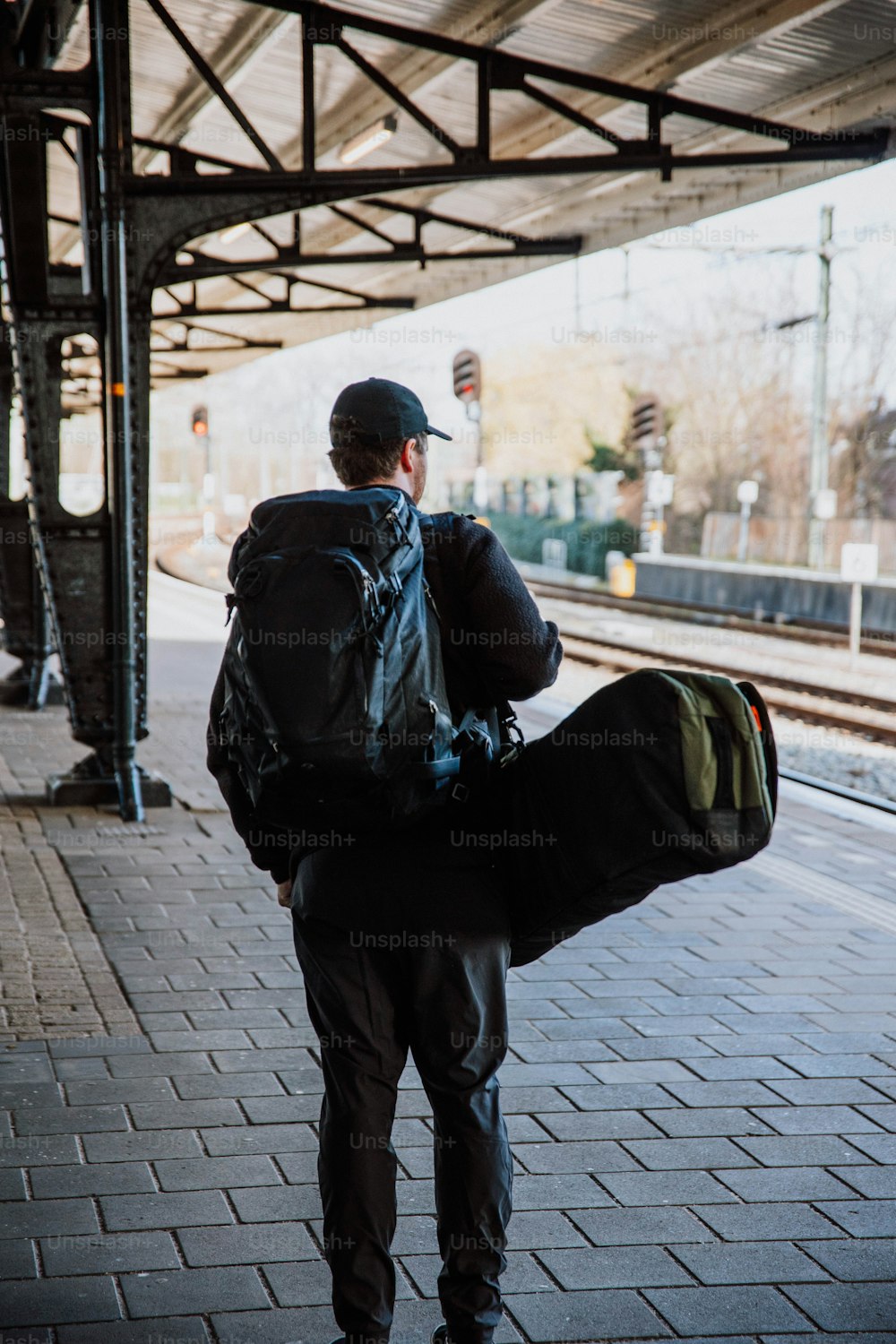 um homem com uma mochila traseira andando por uma plataforma de trem