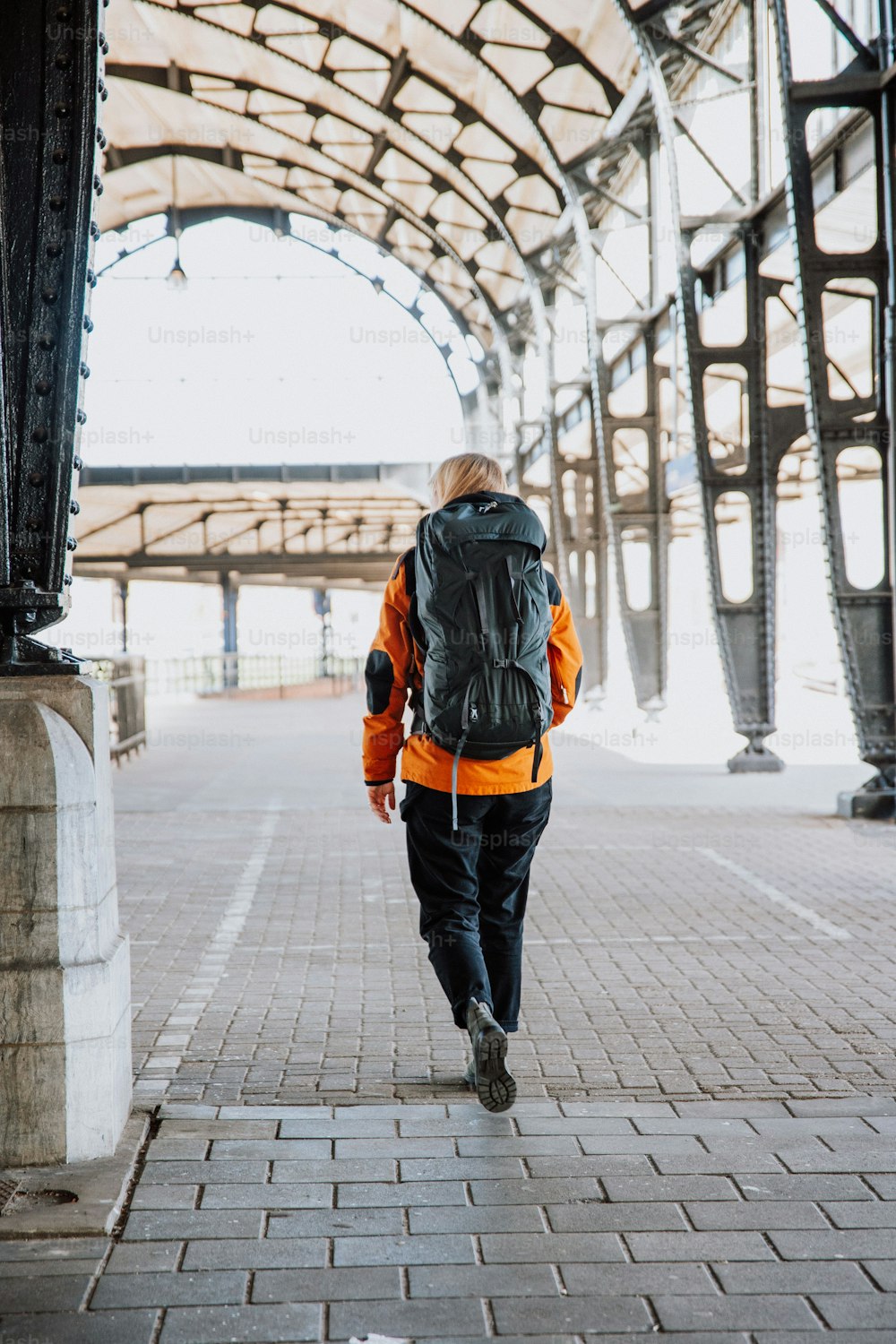 a man with a backpack walking down a walkway