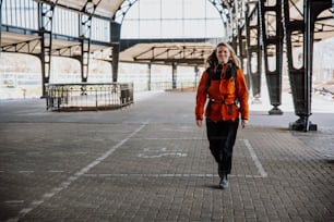 a woman in an orange jacket is walking down the street