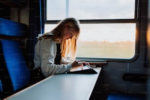 a woman sitting on a train looking at a book